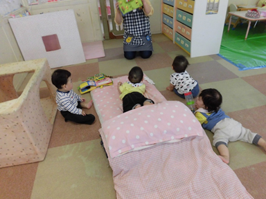 ありぐみの子どもがハイハイで保育者のところに集まっている様子