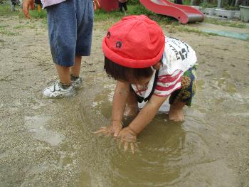 泥水に触れて心地よさを味わう子ども