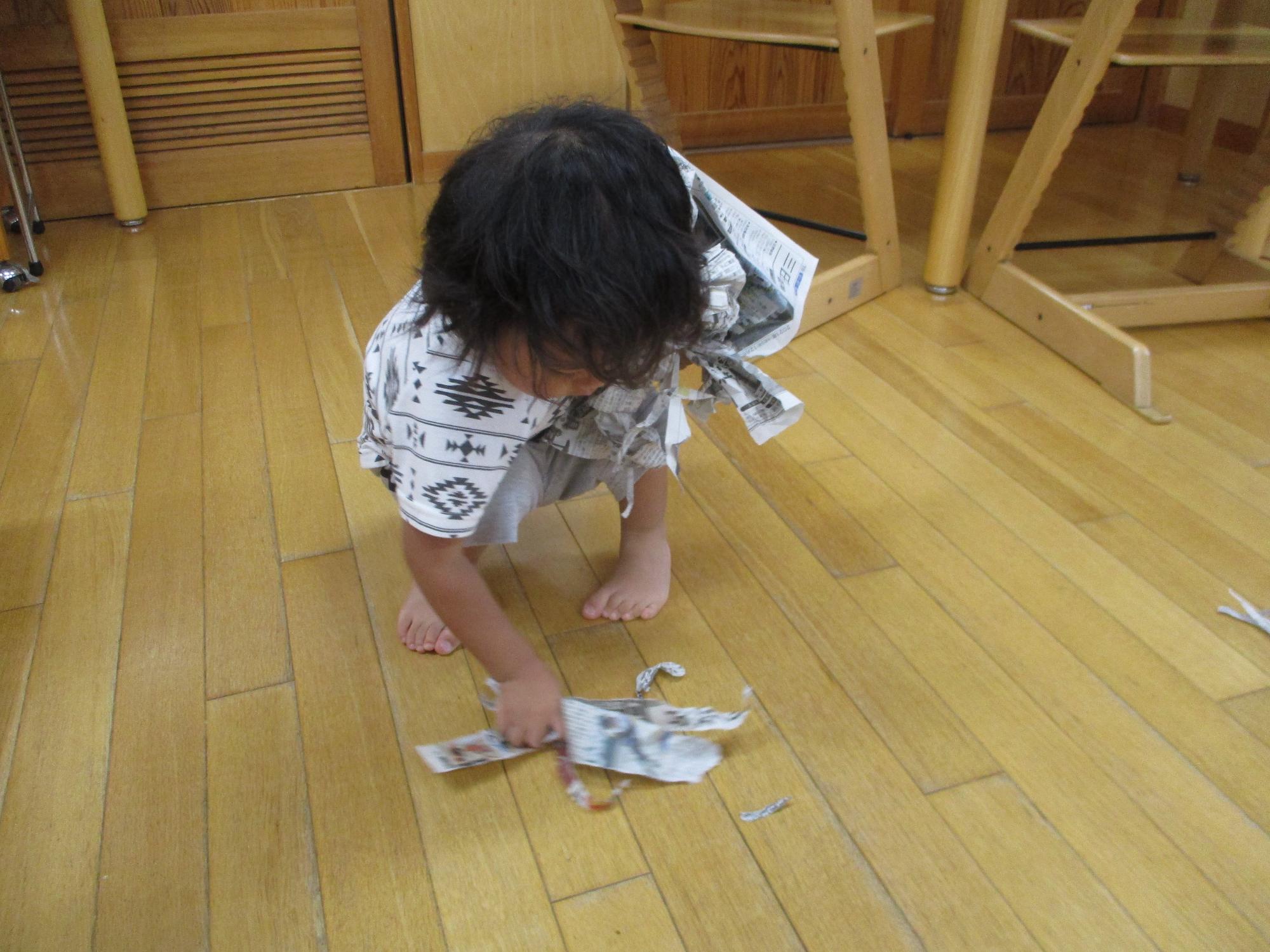 破いた新聞紙を拾う子ども