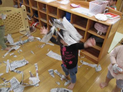 破いた新聞紙を上から落とす子ども