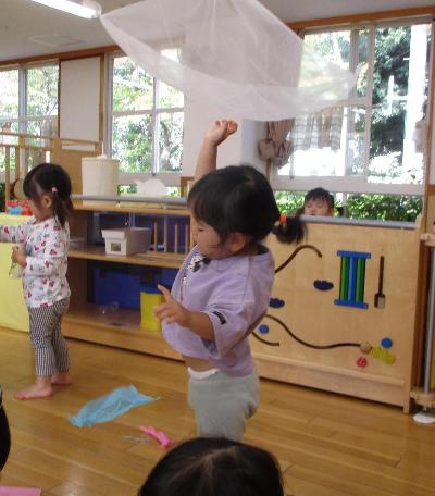 花紙を持ち上げて頭の上から落とす子ども