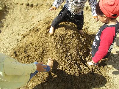 裸足で砂場の土の感触を楽しむ子ども達