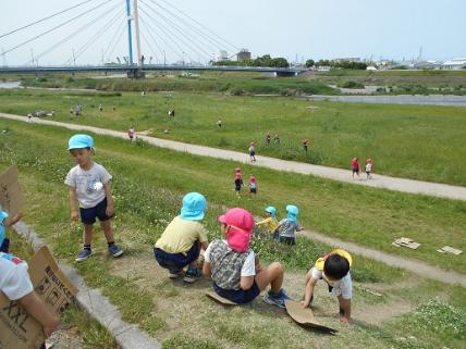 河川敷で坂滑りするこども