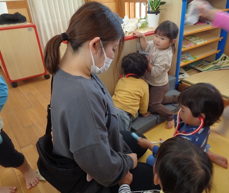 保育者に聴診器を当てる子ども