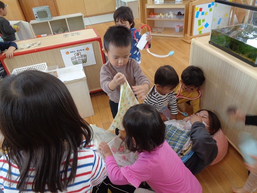 保育者に布団をかける子ども