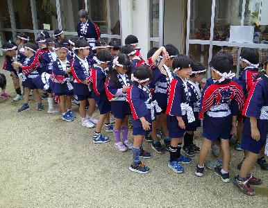 幼年消防クラブ組替式で法被を着て整列している。