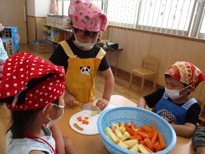 人参とじゃがいもを切っている子ども