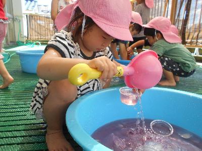ジュースに見立てて色水をカップに入れることを楽しんでいる様子