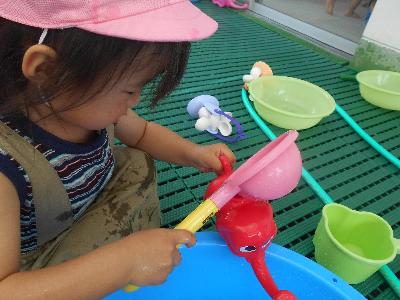 みつばち組の子どもが手桶を使ってじょうろに水を入れている画像