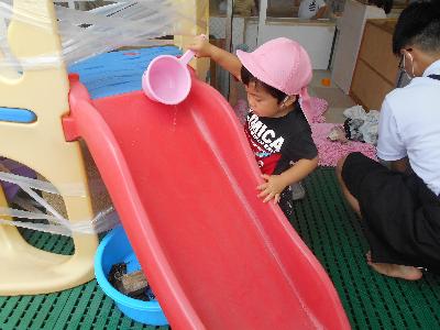 みつばち組の子どもが手桶で滑り台に水を流している画像