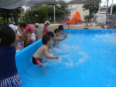 子どもたちがプールの中で水のかけ合いっこをしています