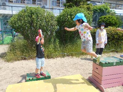 5歳児が高さ約1メートルの台上からジャンプして、4歳児が持つタンバリンをタッチする。