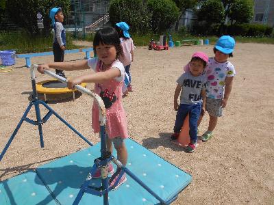 鉄棒で前回りをしようとしている5歳児