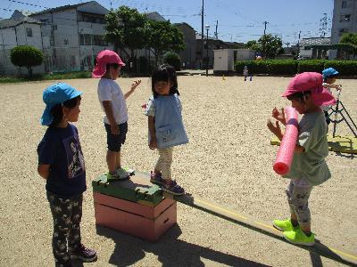 4歳児が一本橋を渡る様子を見守る5歳児