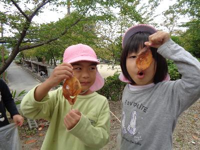 落ち葉に穴をあけてお面に見立てて遊ぶ子ども達