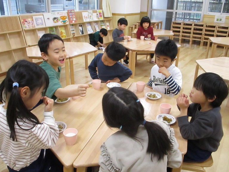 子どもたちが机を囲んでおやつのフライド大根を食べている
