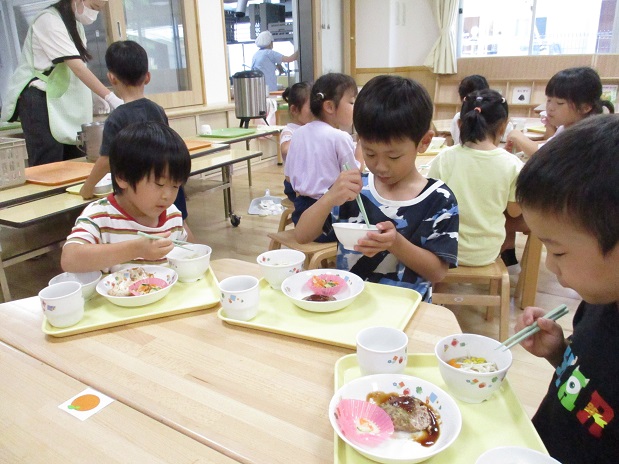 こども達3人がテーブルを囲んで食べている様子。