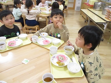 こどもたちがテーブルを囲んで楽しそうに食べている様子。