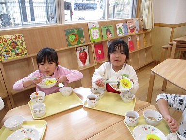 こどもたちがテーブルを囲んで楽しそうに食べている様子。