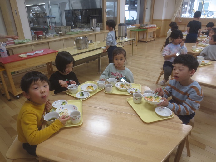 こどもたちがテーブルを囲んで楽しそうに食べている様子。