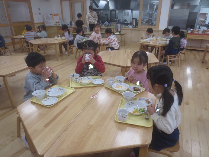 机を囲んで子どもたちが給食を楽しそうに食べている様子