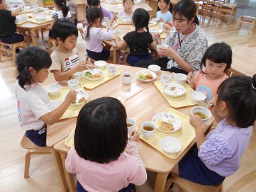こどもたちがテーブルを囲んで食べている様子。
