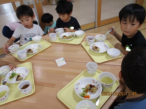 こどもたちがテーブルを囲んで楽しそうに食べている様子。