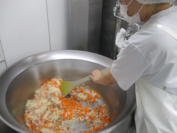 回転窯で、豚肉、人参、玉ねぎを炒めている。